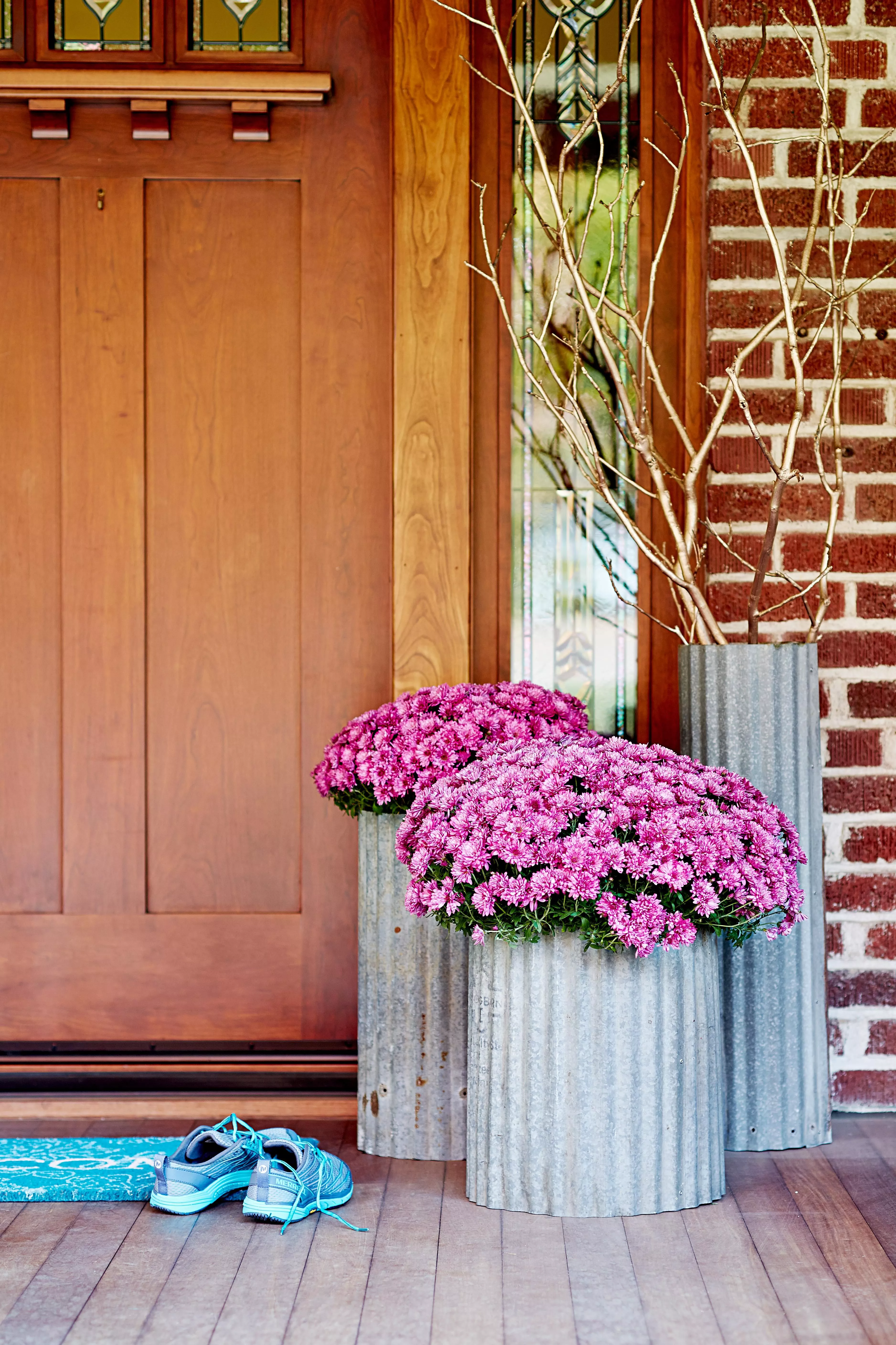 Pots en métal galvanisé avec des chrysanthèmes roses sur le porche